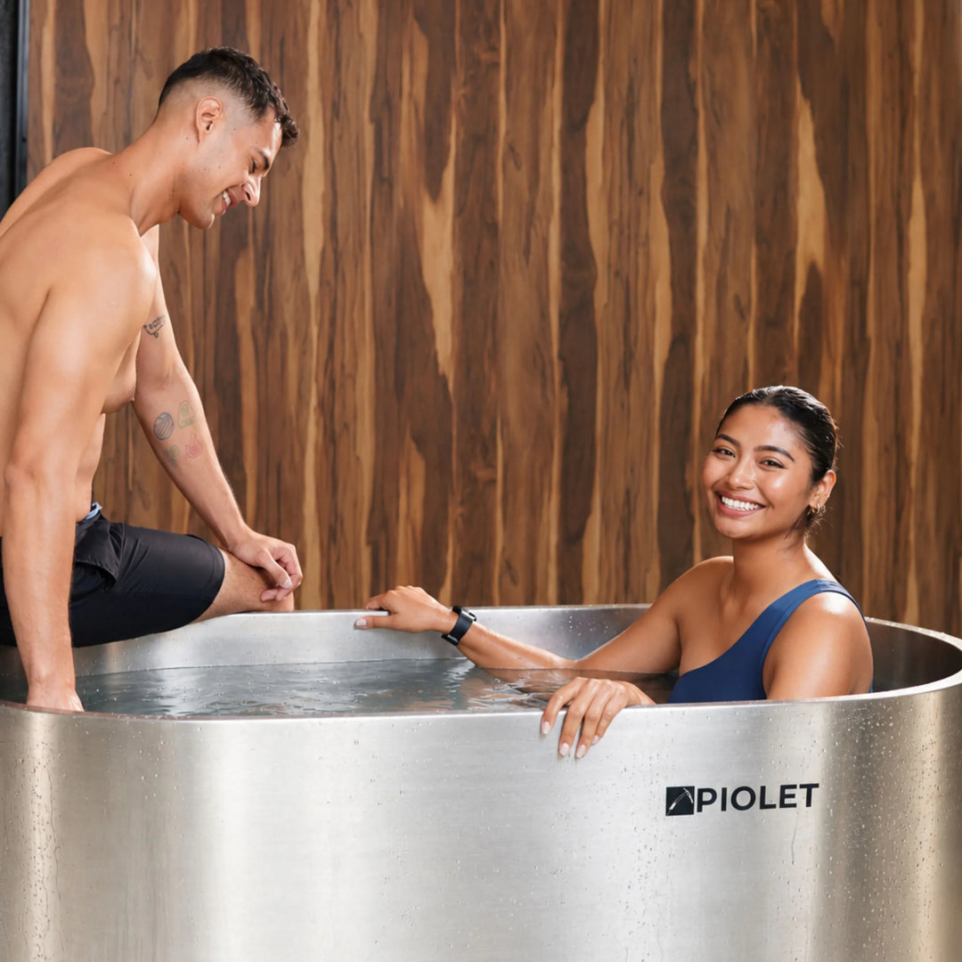 Pareja junto a la tina fija PIOLET Steel en un spa con paredes de madera
