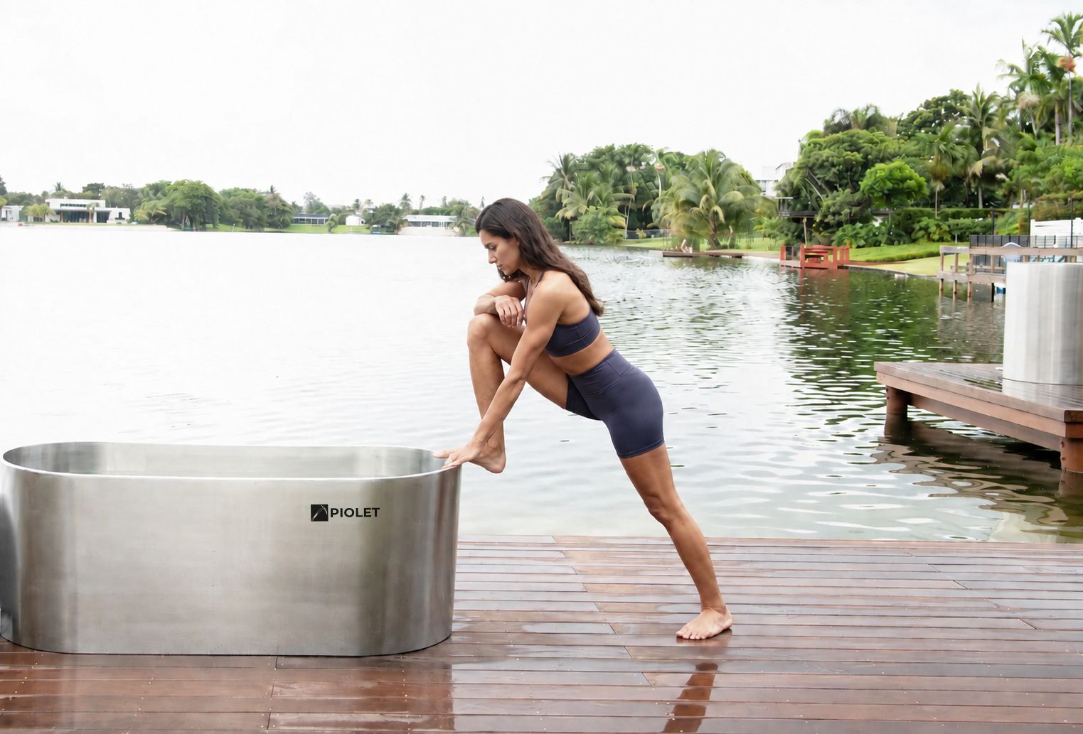 Mujer deportista junto a PIOLET Steel de acero inoxidable 304 en un deck de madera frente a un lago