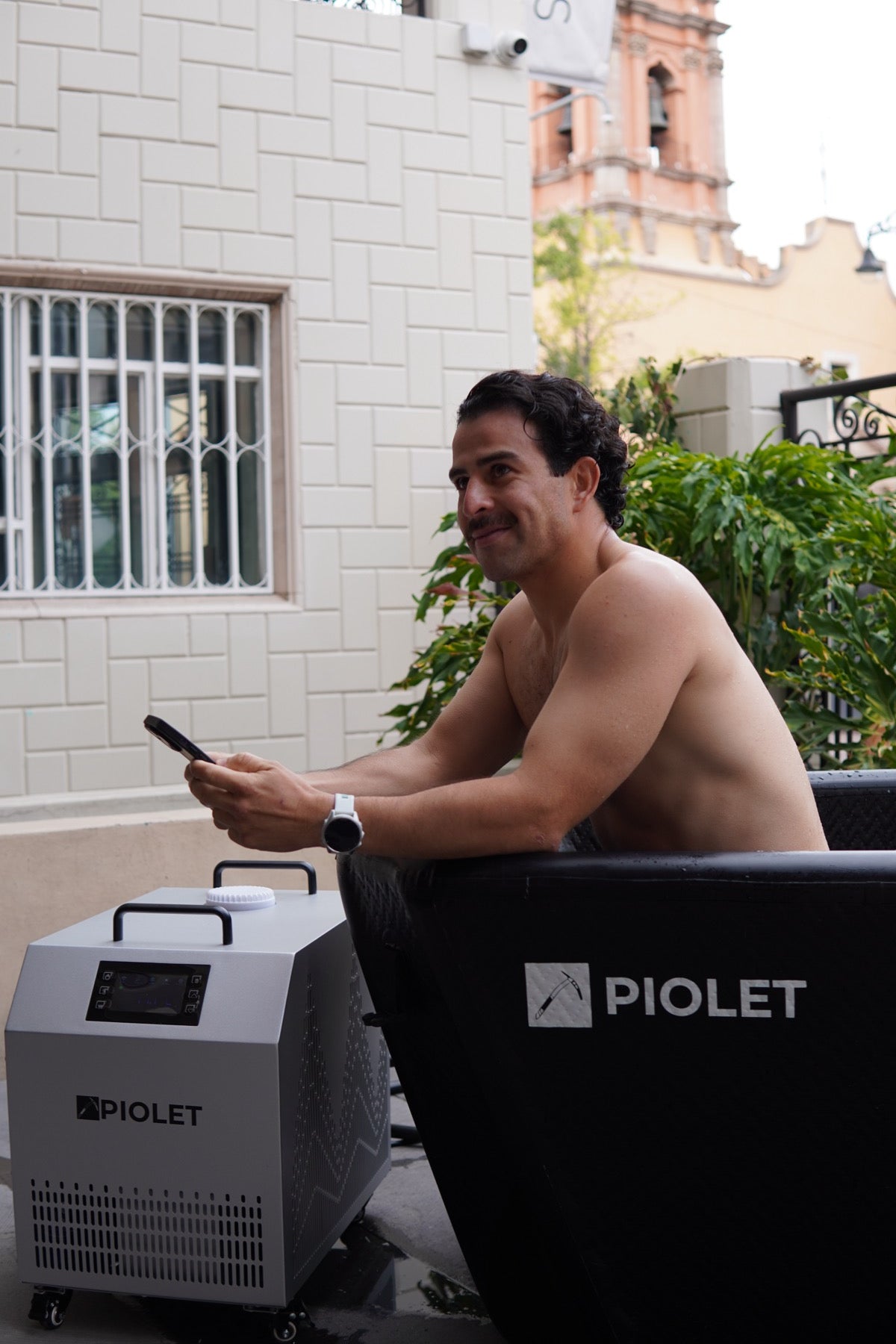 Man in a PIOLET tub with his phone, next to the Polar PRO chiller