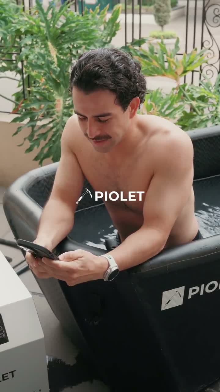 Man in a PIOLET tub at home using his phone, with the Polar PRO chiller beside it